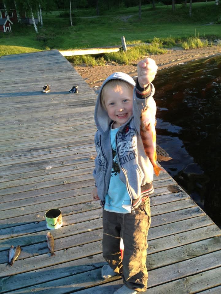 Nathan som liten håller upp en abborre på bryggan i kvällssol