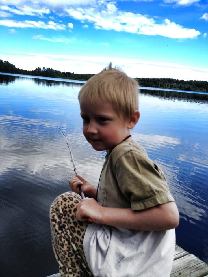 Nathan med metspöt på bryggan, spegelblank sjö bakom.